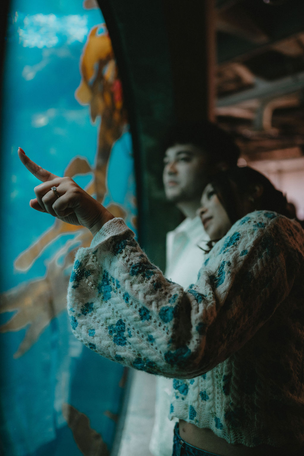 Couple pointing into fish tank during Monterey Bay Aquarium cinematic engagement session