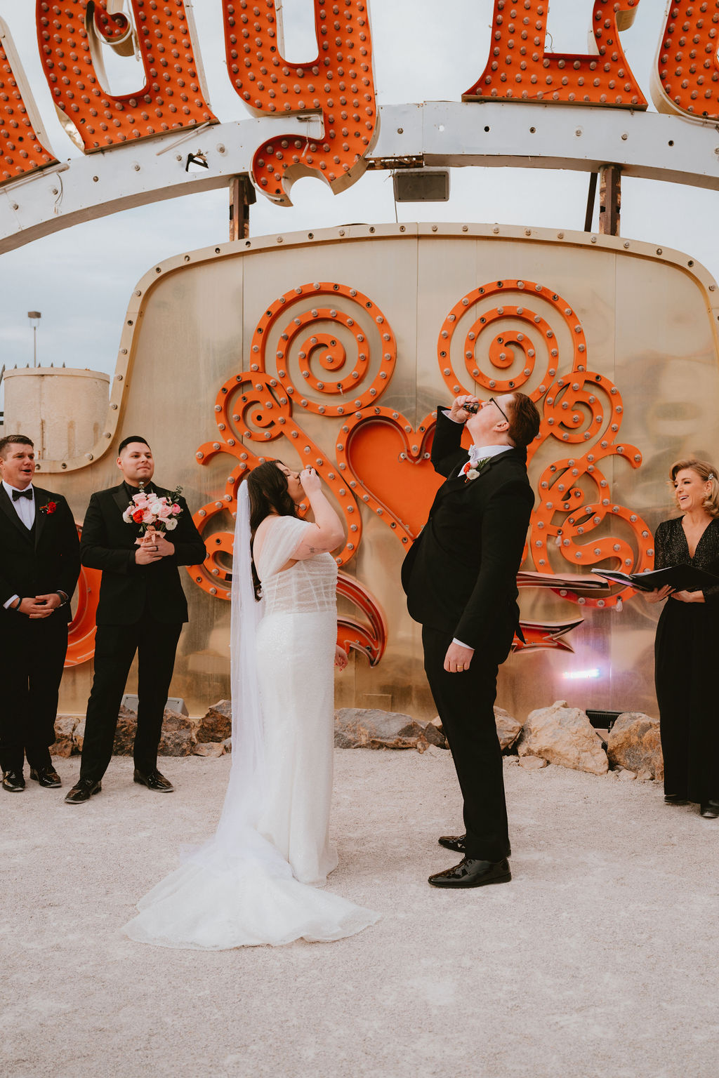 Bride and a groom take a shot at their Neon Museum wedding