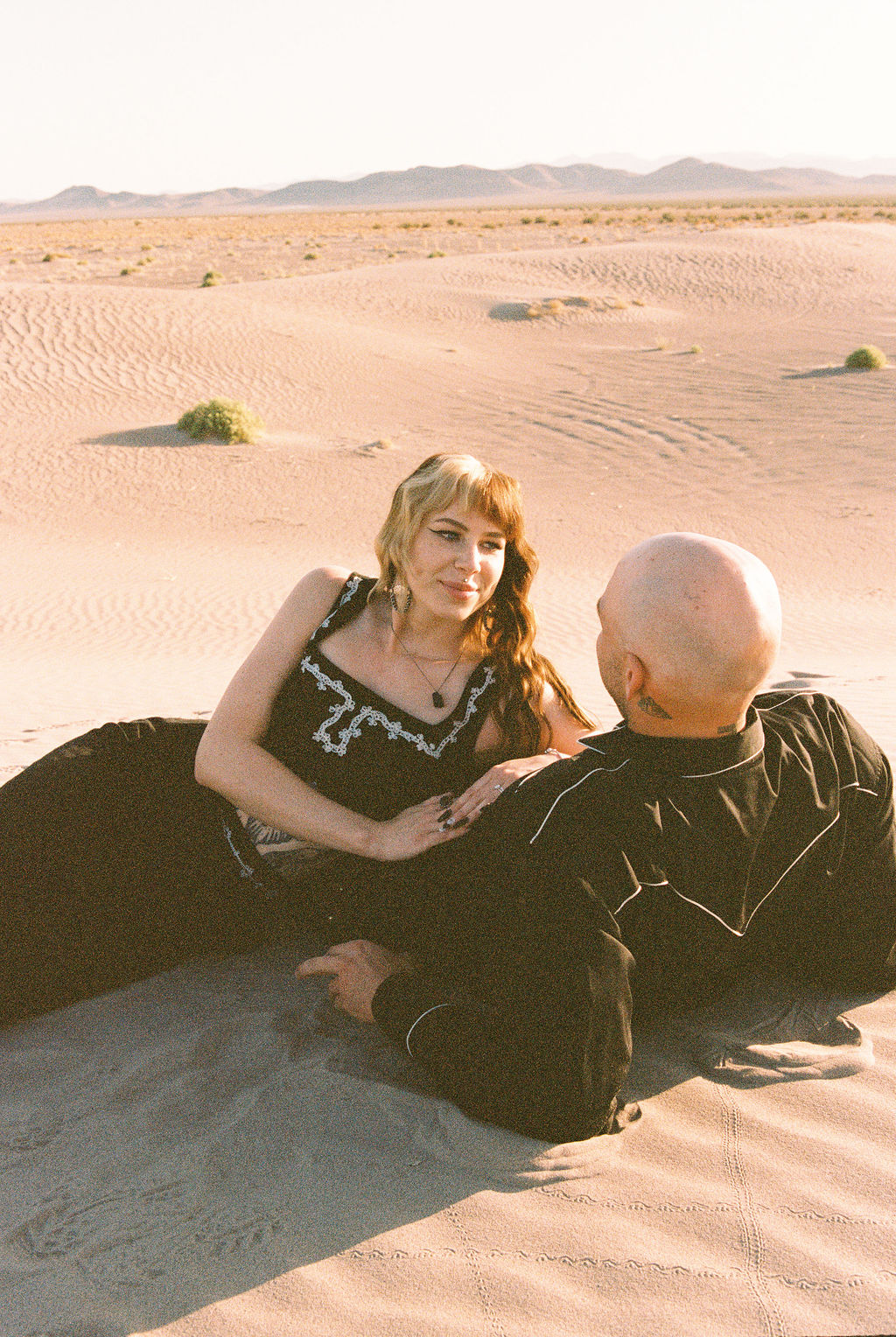 Man and woman laying on sand dune in Amargosa Valley
