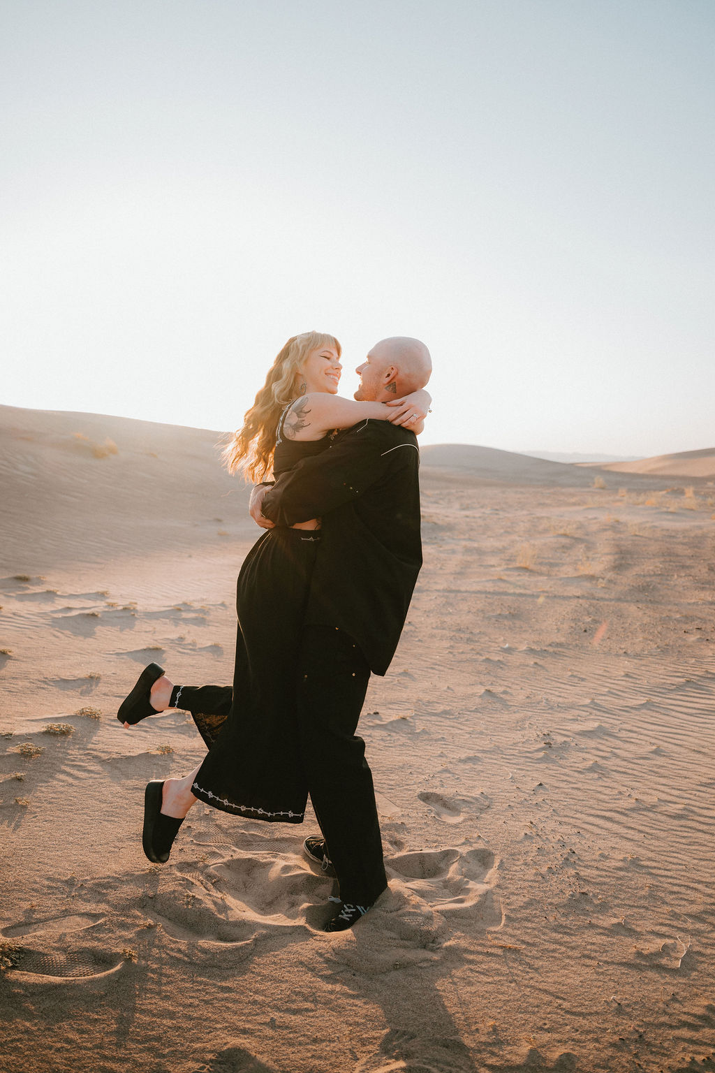 Man lifts woman and spins her in the air during Amargosa Valley engagement photos