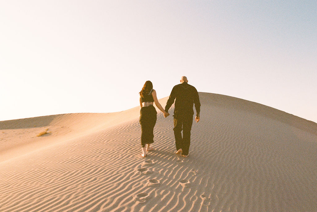 Couple walking on a sand dune at Amargosa Valley engagement photoshoot